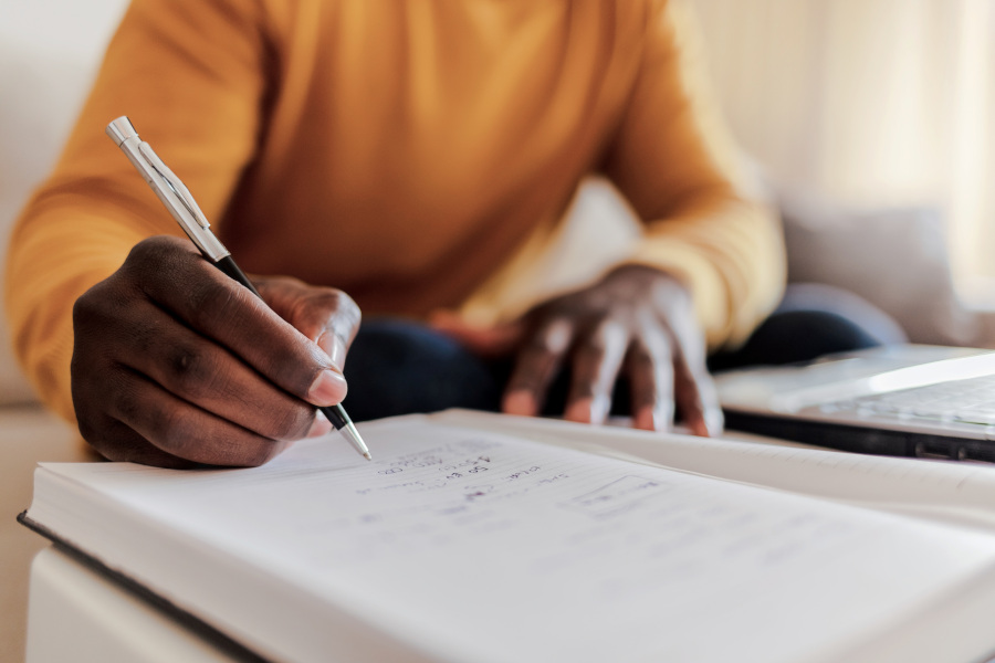 Hand writing with computer in the background.
